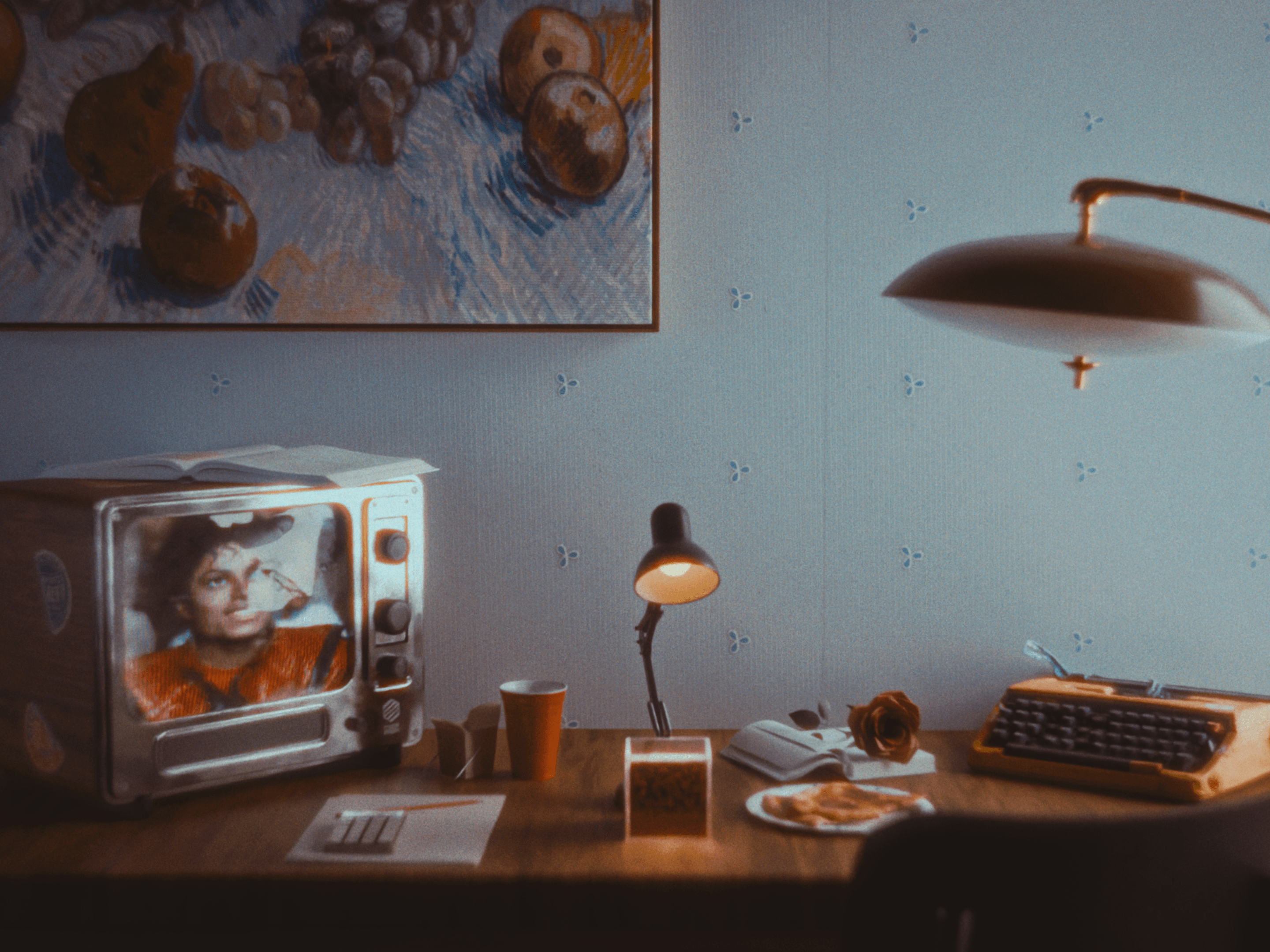 A cubesat under a lamp on a cluttered desk.
